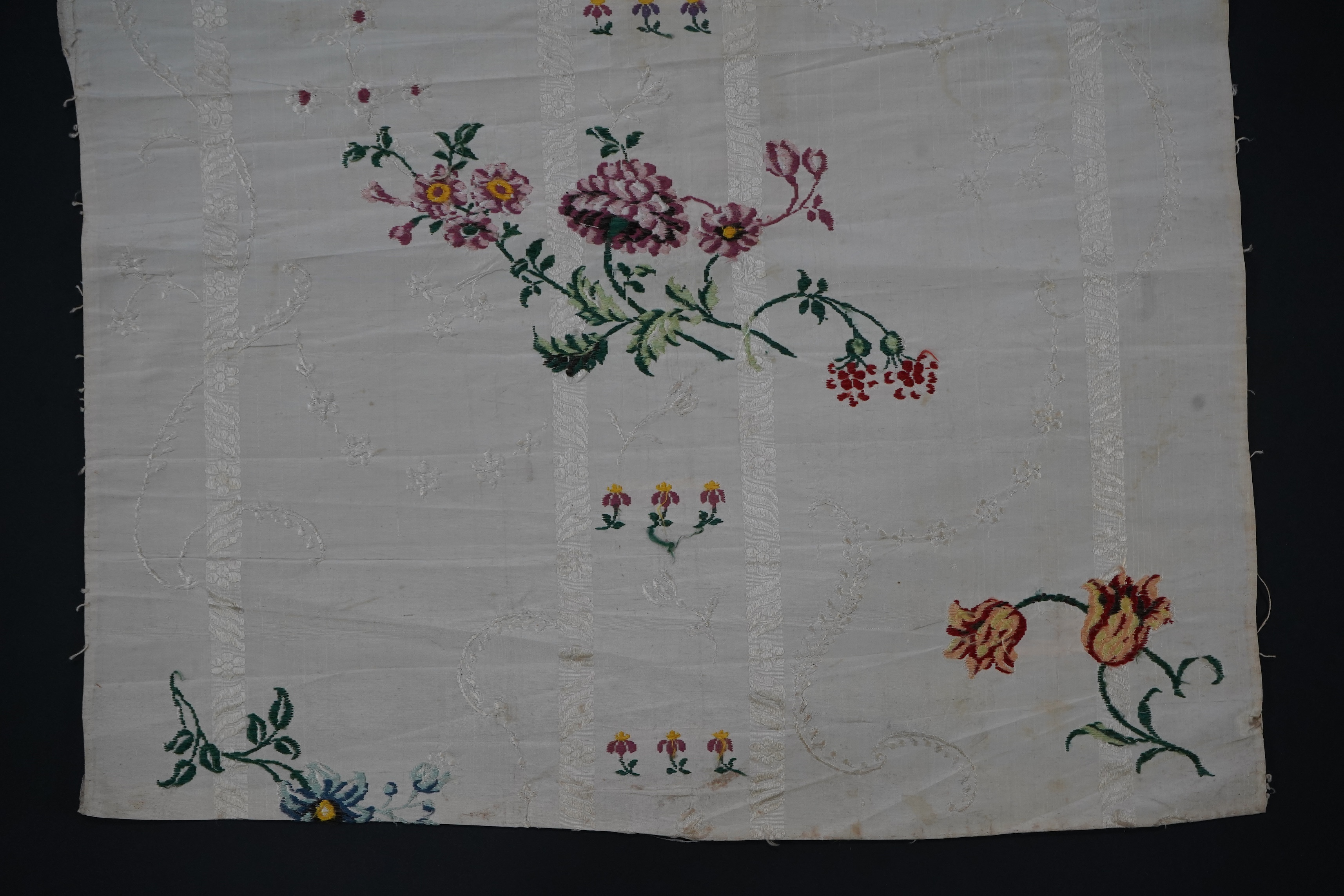 A length of 18th century short loom hand woven Spitalfields silk dress fabric, woven in cream silk with all over multicoloured spot floral motifs in a large repeat. 82cm repeat, total length of fabric 100cm x 48.5cm wide